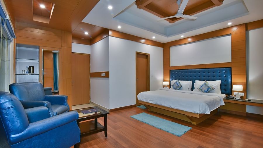 A large bed placed in front of two sofas at the Luxury Room Without Balcony at DLS Highland Resort and Spa, Mussoorie.